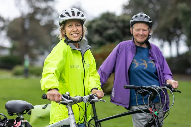 a couple of women standing next to each other with bikes
